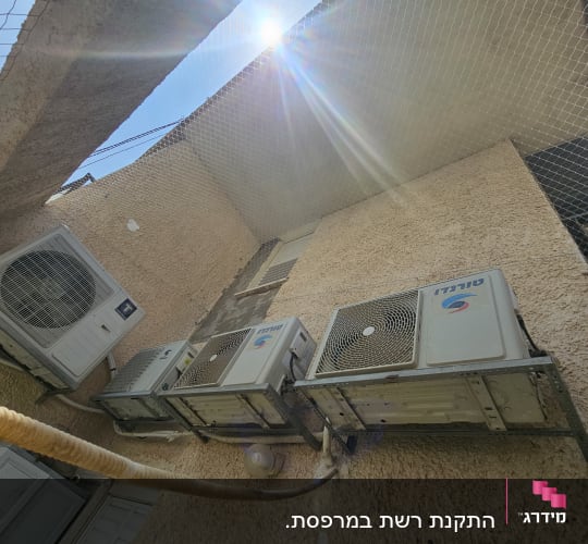 רשת מונעת יונים מעל מזגנים על קיר חיצוני